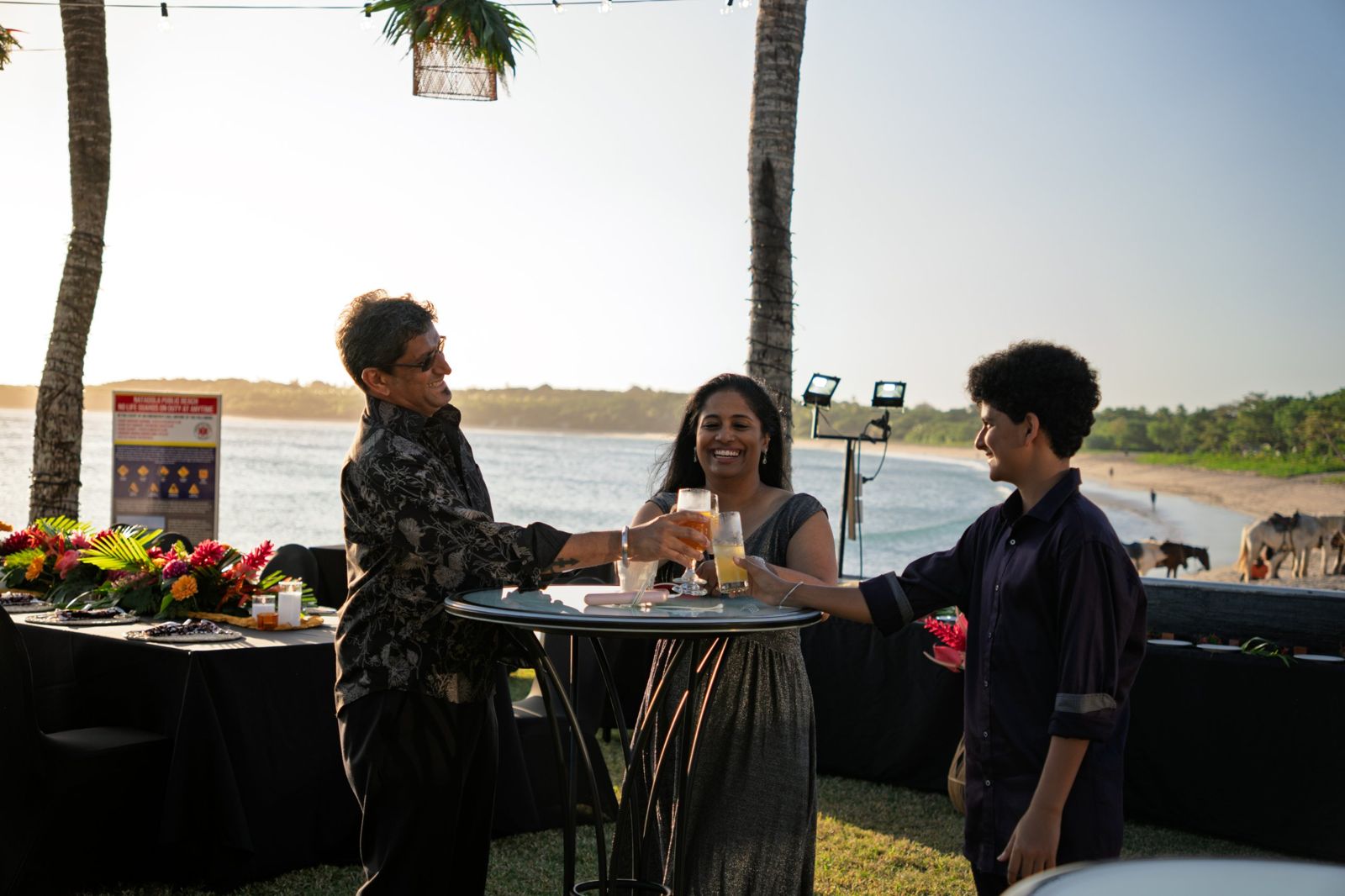 Family raising glasses at a sunset cocktail table on Natadola beach
