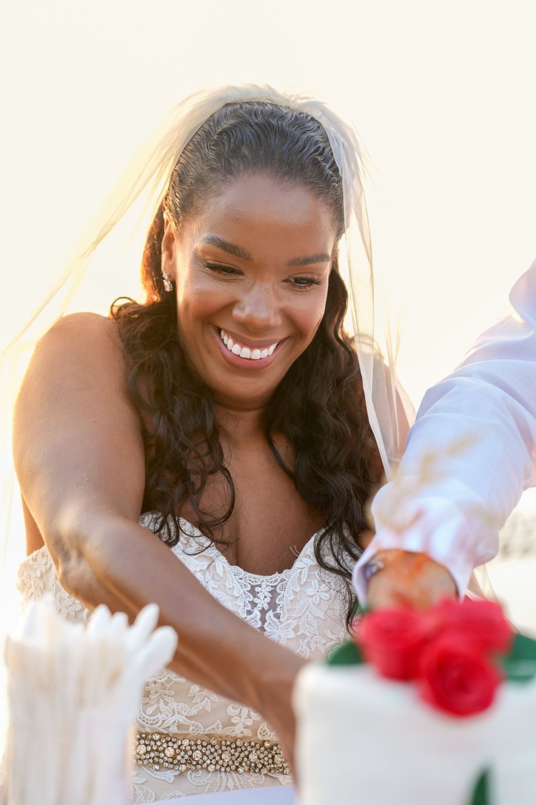 Bride laughing as she cuts the cake