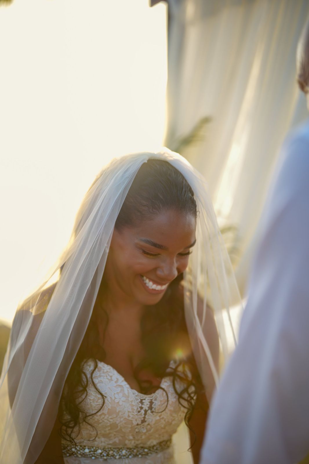 Bride laughing beneath her veil in golden light