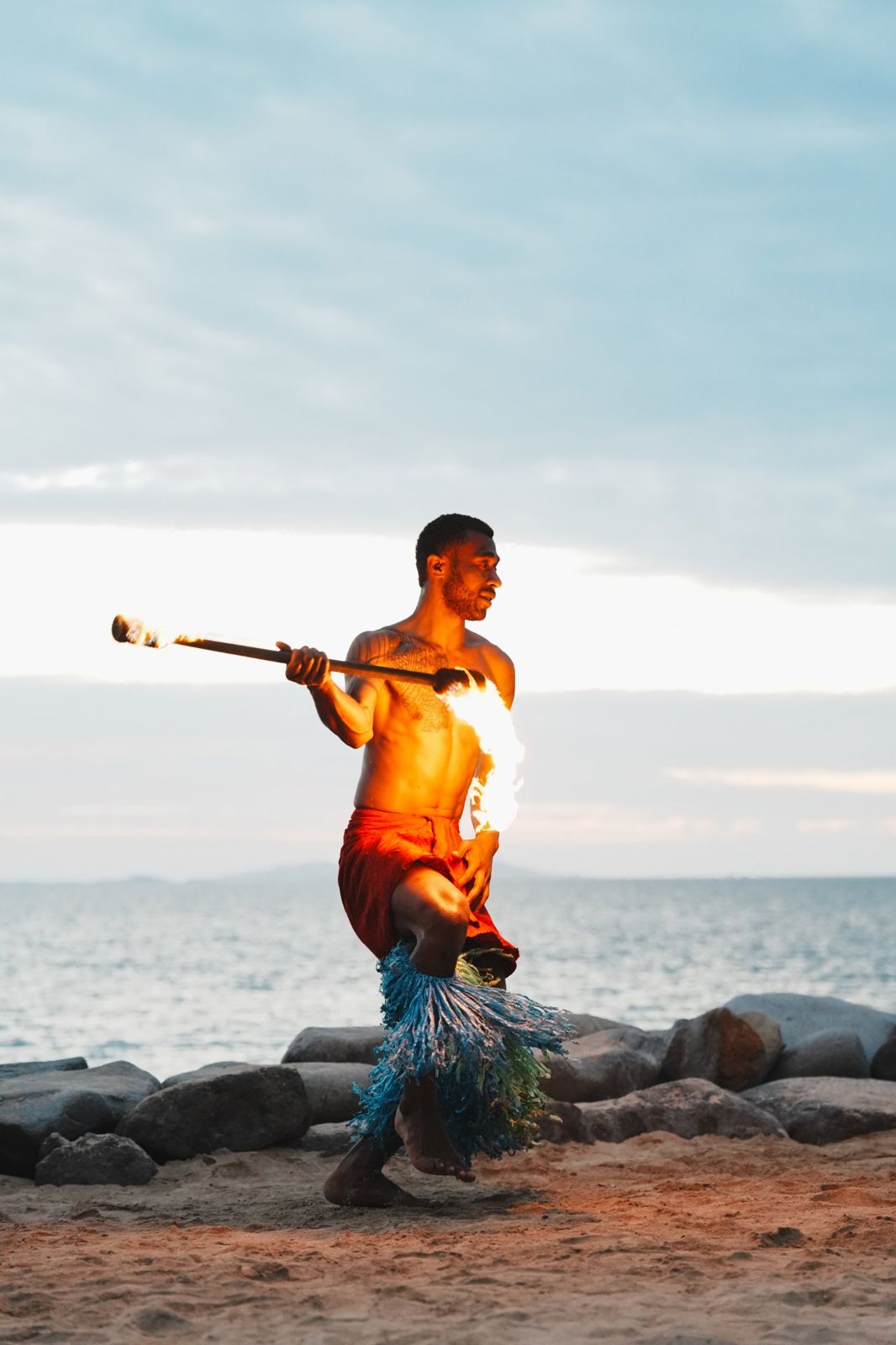 Fire dancer performing on the beach at dusk
