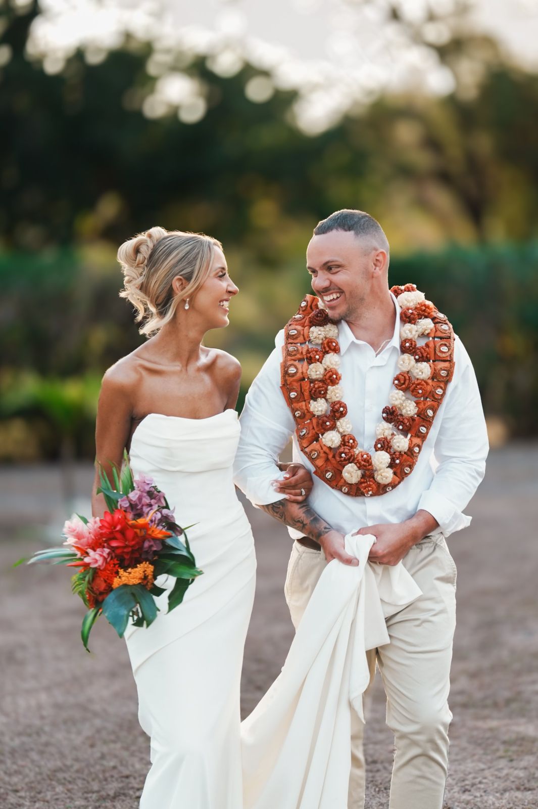 Bride and groom laughing together, groom wearing a salusalu garland