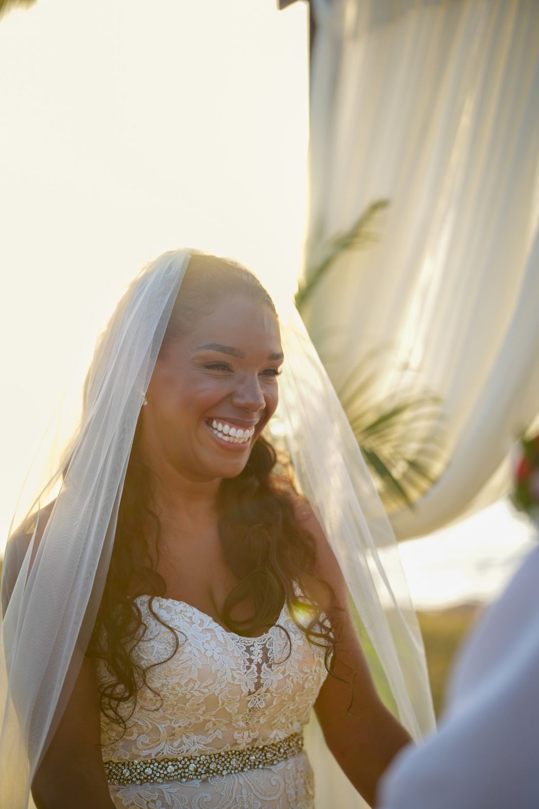 Bride smiling beneath her veil in warm evening light