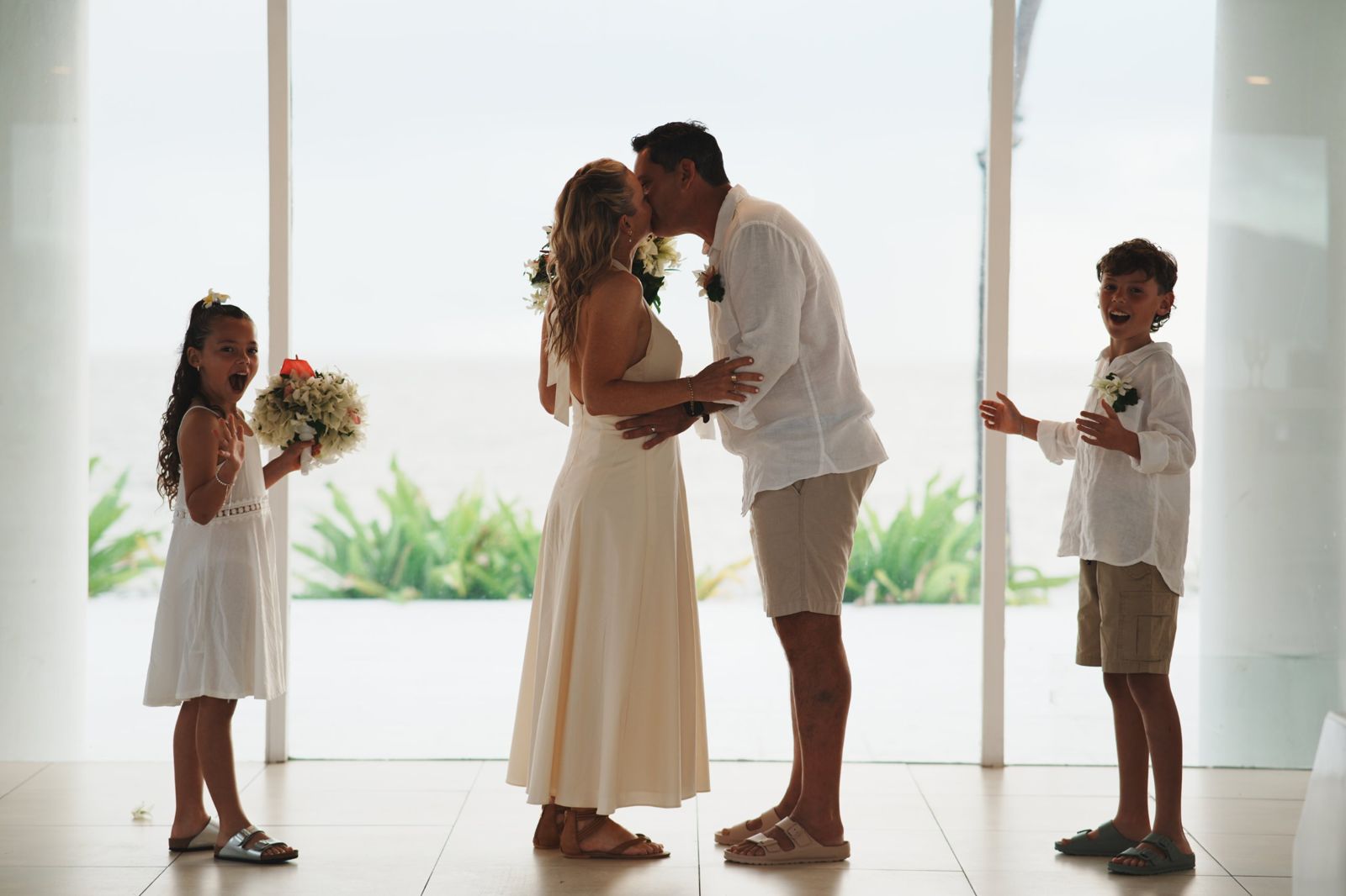 Couple kissing at their wedding while their two children cheer
