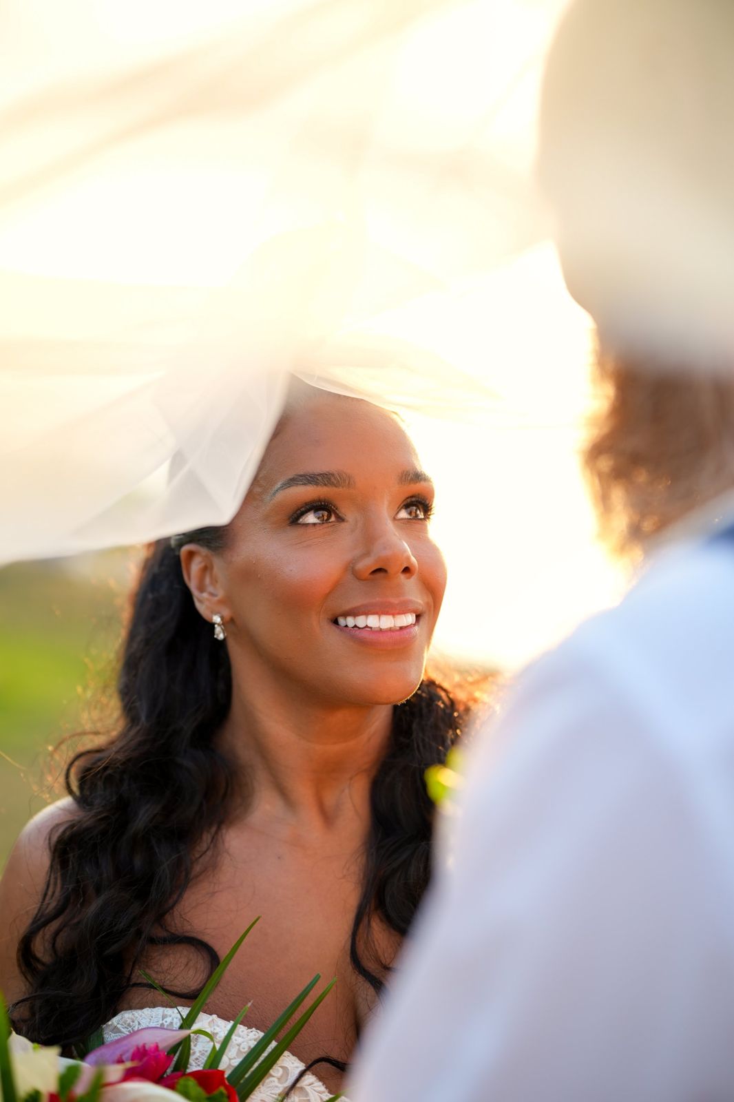 Bride looking up at her groom beneath a sunlit veil
