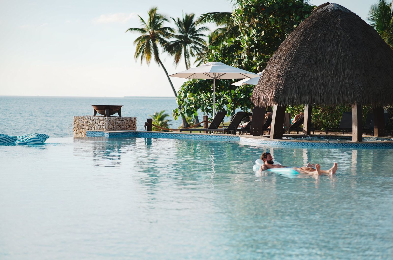 Guest floating in a resort infinity pool beside the sea