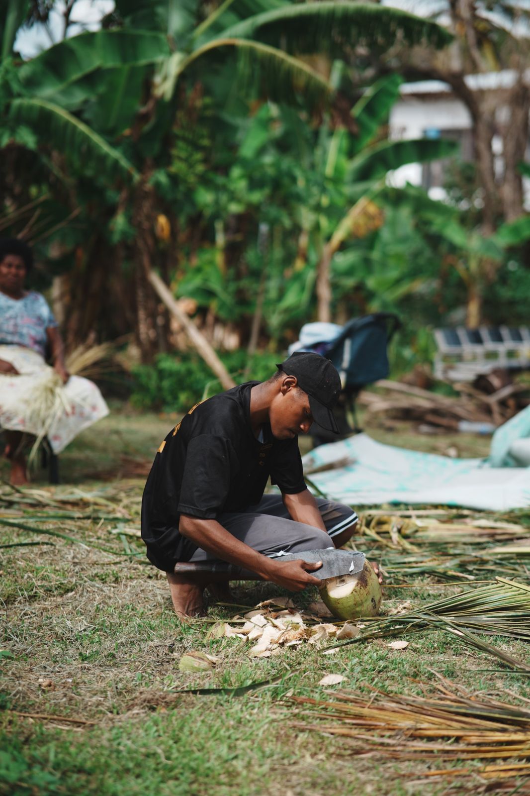 Young man husking a coconut in a village